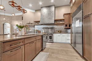 Kitchen featuring open shelves, high end appliances, dark stone counters, hanging light fixtures, and arched walkways