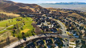 Aerial view of property and surrounding area featuring nearby suburban area, a mountain backdrop, and a golf club
