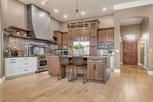 Kitchen with backsplash, a breakfast bar, open shelves, decorative light fixtures, and stainless steel built in refrigerator