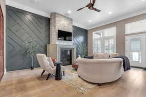 Living area with crown molding, light wood finished floors, ceiling fan, a fireplace, and recessed lighting