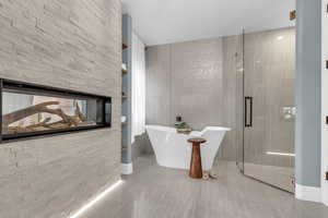 Bathroom with tile walls, a stall shower, a soaking tub, and built in features