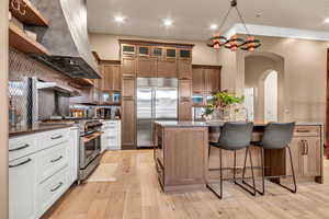 Kitchen featuring arched walkways, stainless steel appliances, brown cabinets, tasteful backsplash, and recessed lighting