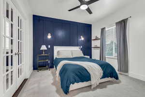 Carpeted bedroom featuring a decorative wall, ceiling fan, and an accent wall