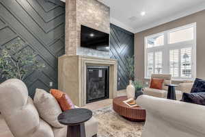 Living area with a fireplace, crown molding, and wood finished floors