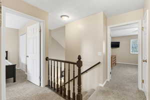 Hall with light carpet and an upstairs landing