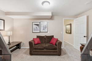 Living area with light colored carpet and a textured ceiling