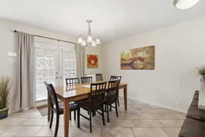Dining area with a chandelier, french doors, and light tile patterned flooring
