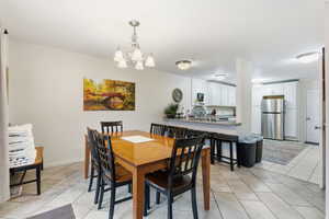 Dining area with light tile patterned flooring and a chandelier