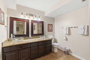 Full bath with double vanity and dark tile patterned floors