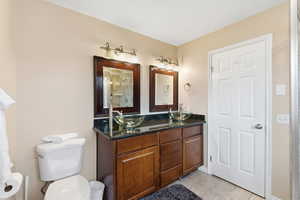 Full bathroom featuring double vanity, light tile patterned flooring, and a shower with door