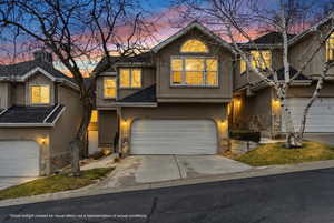 Traditional home featuring stone siding, stucco siding, driveway, and a garage