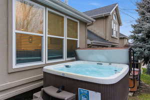 View of property exterior with a hot tub, stucco siding, and a wooden deck