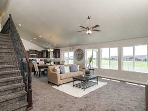 Living area featuring vaulted ceiling, stairway, carpet flooring, a ceiling fan, and a chandelier