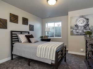 Bedroom with dark carpet and a textured ceiling