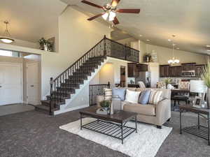 Living area with high vaulted ceiling, stairs, a chandelier, dark colored carpet, and ceiling fan