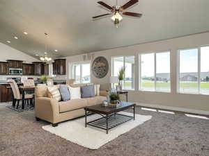 Living room with vaulted ceiling, a chandelier, a ceiling fan, light carpet, and recessed lighting