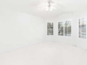 Carpeted spare room with vaulted ceiling and a ceiling fan