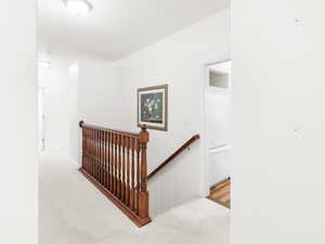 Hallway with an upstairs landing and carpet
