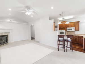 Kitchen with open floor plan, a kitchen bar, recessed lighting, dark carpet, and brown cabinetry