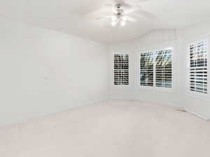 Living room off the front entryway featuring light colored carpet, ceiling fan, and lofted ceiling