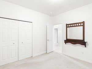 Unfurnished bedroom with light carpet and a closet