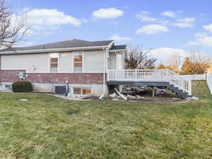 View of property exterior featuring brick siding, a deck, a yard, and stairway