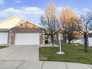 Single story home featuring brick siding, a front yard, a garage, and driveway