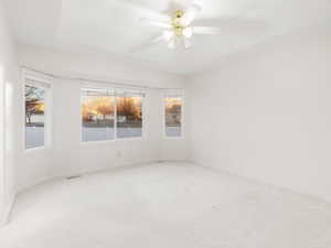 Carpeted empty room with ceiling fan and baseboards