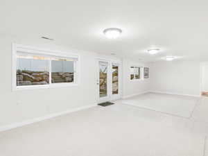 Basement with baseboards and light colored carpet