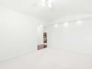 Carpeted spare room featuring arched walkways and a ceiling fan