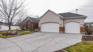 Ranch-style home featuring driveway, an attached garage, stucco siding, and a shingled roof