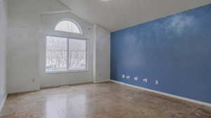 Empty room featuring lofted ceiling and baseboards