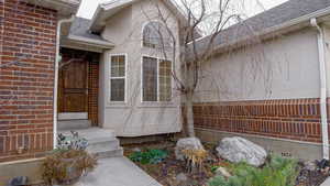 Property entrance featuring a shingled roof and brick siding