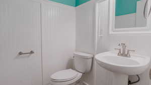 Half bath with a decorative wall and a wainscoted wall