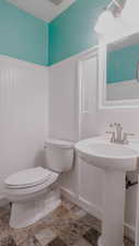 Half bathroom with wainscoting and a decorative wall