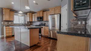 Kitchen with tile countertops, stainless steel appliances, pendant lighting, light brown cabinetry, and decorative backsplash
