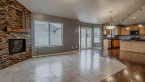 Kitchen featuring a stone fireplace, dark tile patterned floors, decorative light fixtures, open floor plan, and recessed lighting