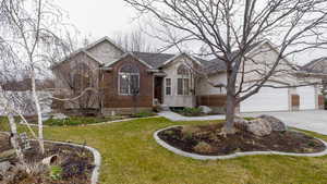 View of front facade with brick siding, driveway, a front lawn, and an attached garage