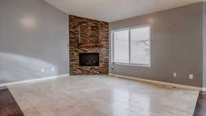 Unfurnished living room featuring vaulted ceiling and a large fireplace
