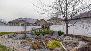 Fenced backyard featuring a garden pond