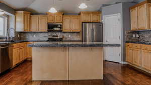 Kitchen featuring appliances with stainless steel finishes, pendant lighting, tasteful backsplash, tile counters, and vaulted ceiling
