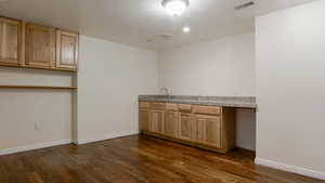 Kitchen with dark wood-type flooring and light brown cabinetry