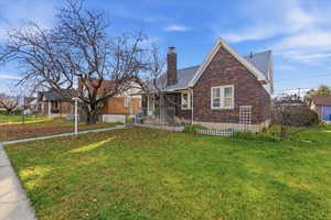 View of front facade featuring a front lawn, brick siding, and a chimney