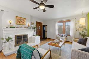 Living area with a fireplace, wood finished floors, and a ceiling fan
