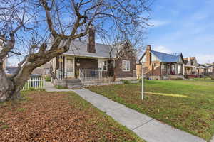 View of front of house with a chimney, brick siding, a front lawn, and a porch