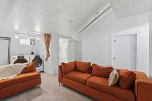Carpeted living room with washing machine and clothes dryer