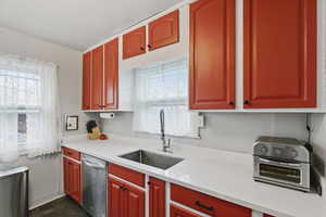 Kitchen with dishwasher, healthy amount of natural light, and light stone countertops