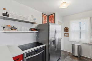 Kitchen featuring stainless steel appliances, open shelves, and light countertops