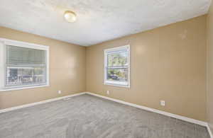 Carpeted spare room featuring baseboards