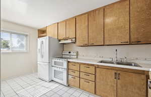 Kitchen featuring white appliances, light countertops, open shelves, light tile patterned flooring, and under cabinet range hood
